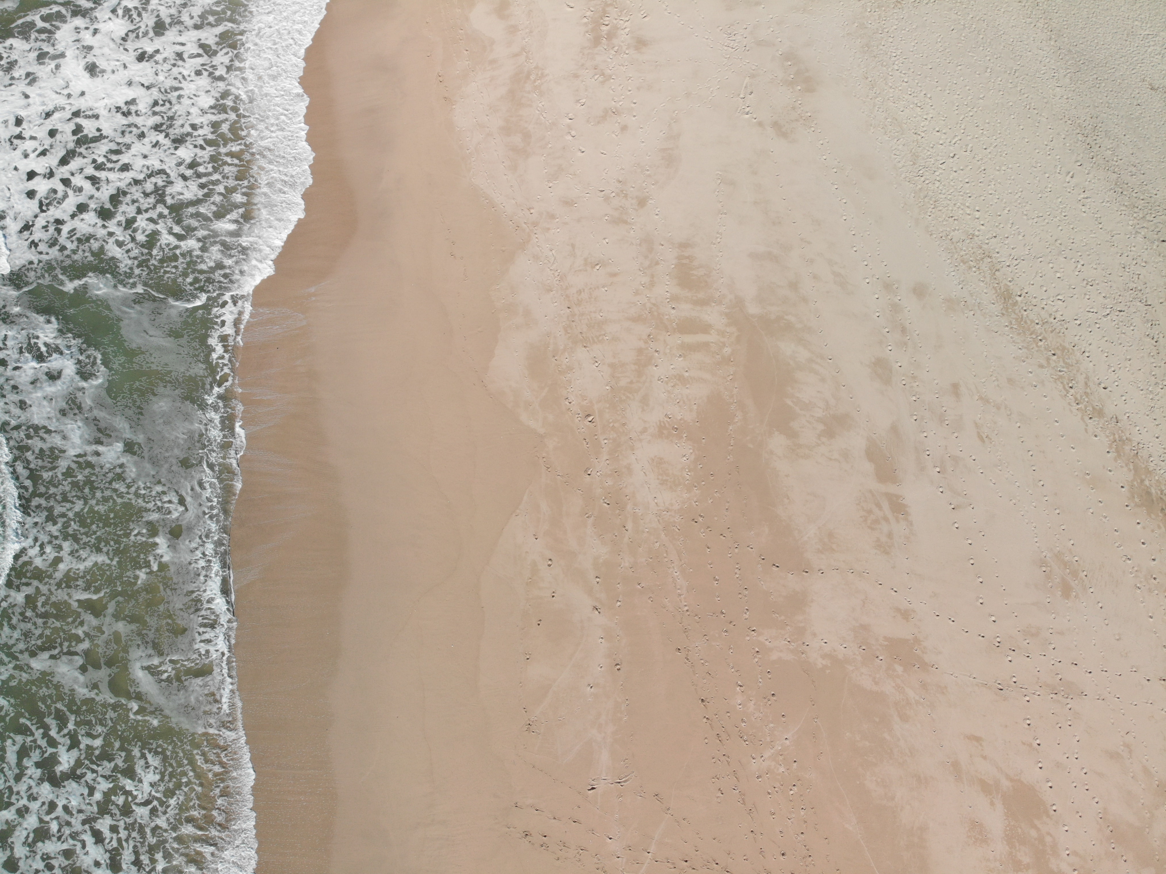 Plage de sable vue du ciel, au bord des vagues
